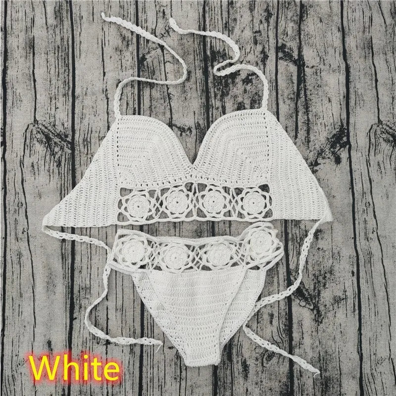 A two-piece white crocheted swimwear set, including a triangle top and cheeky bottoms, laid out flat against a weathered gray wood plank backdrop with a 'White' color label text in the corner.