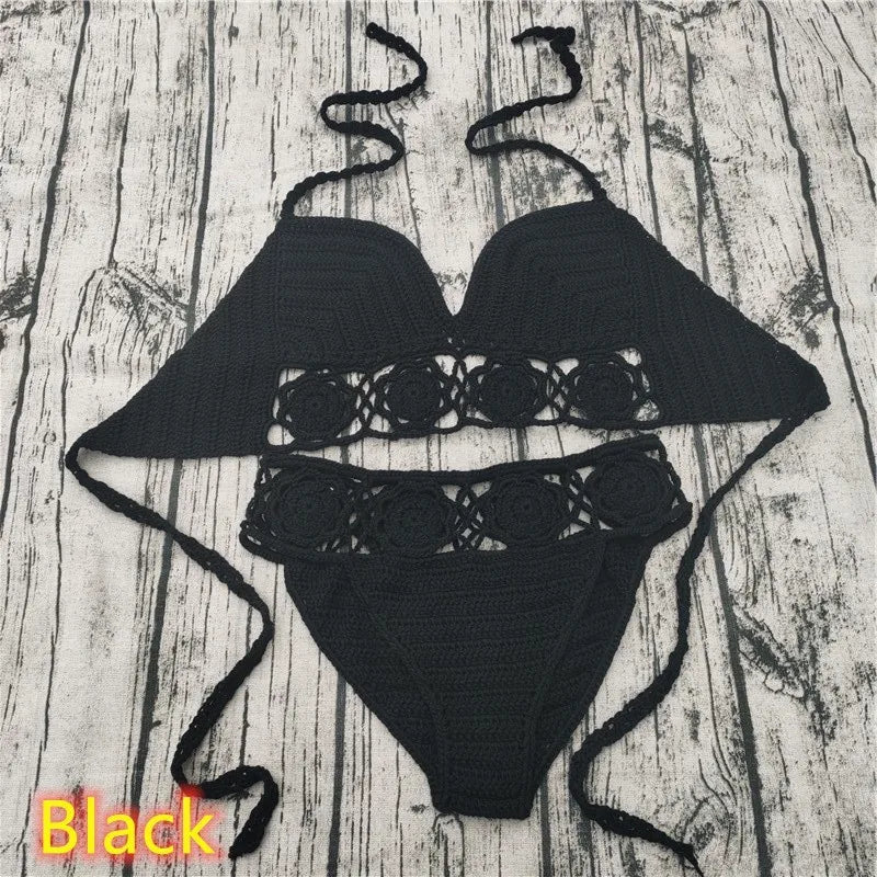A two-piece black crocheted swimwear set, featuring a triangle top and cheeky low-rise bottoms, laid out flat against a weathered gray wood plank backdrop with a 'Black' color label text.