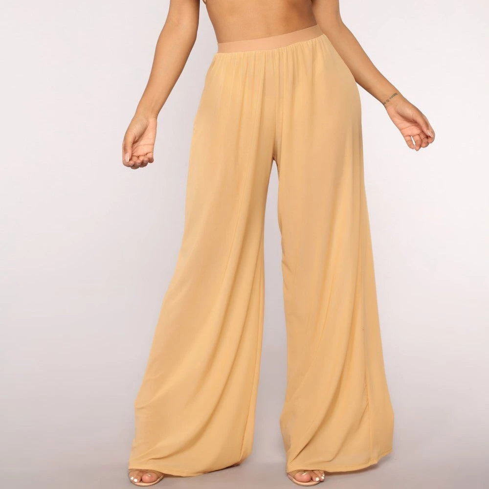 Model wearing Echo & Air women's Sheer Wide Leg Pants in yellow, showcasing the bohemian high-waisted silhouette and loose mesh fabric.