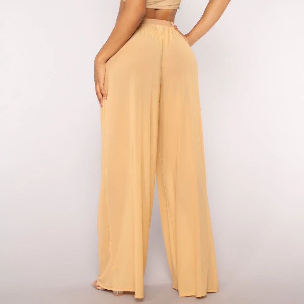 Model from the back wearing Echo & Air women's Sheer Wide Leg Pants in yellow, showcasing the loose bohemian silhouette and sheer mesh fabric.