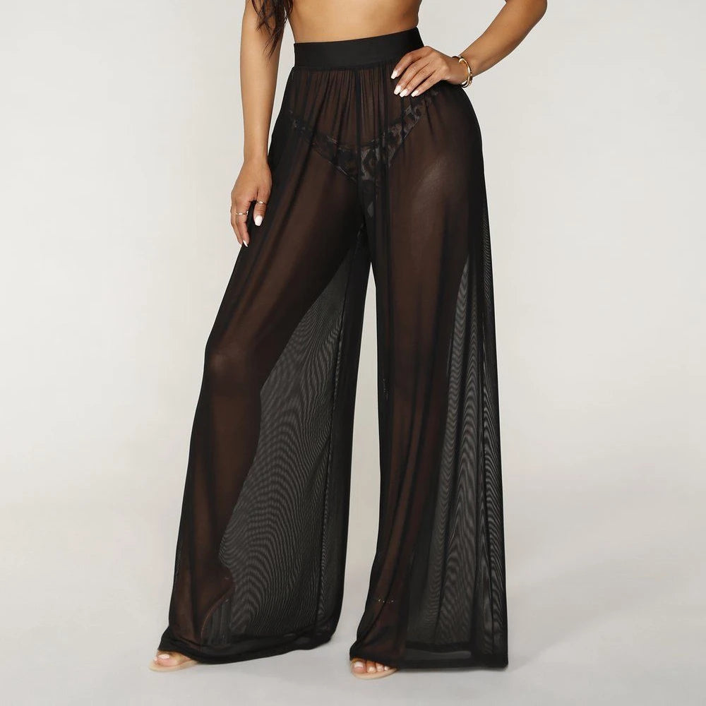 Model wearing Echo & Air women's Sheer Wide Leg Pants in black, showcasing the bohemian high-waisted silhouette and see-through mesh fabric.