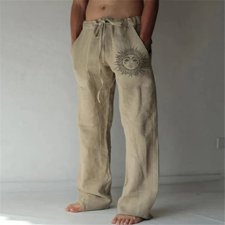 Model wearing Echo & Air men's Driftwood Slit Lounge Pant in beige featuring a prominent graphic sun design on the left leg.
