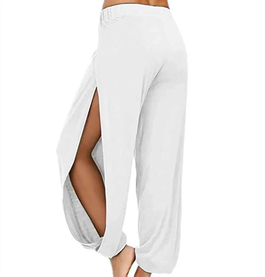 Model from the side wearing Echo & Air women's Ethereal Side-Slit Lounge Pants in white showcasing the high side leg slit and relaxed harem fit.