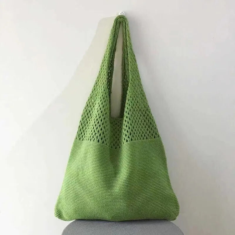 Echo & Air green crochet knit tote bag hanging from a wall hook against a minimalist background