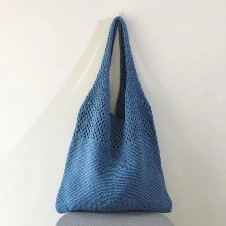 Echo & Air blue crochet knit tote bag hanging from a wall hook against a minimalist background.