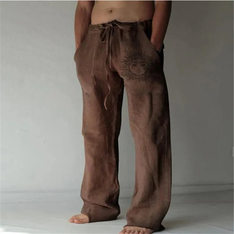 Model wearing Echo & Air men's Driftwood Slit Lounge Pant in brown featuring a prominent graphic sun design on the left leg.