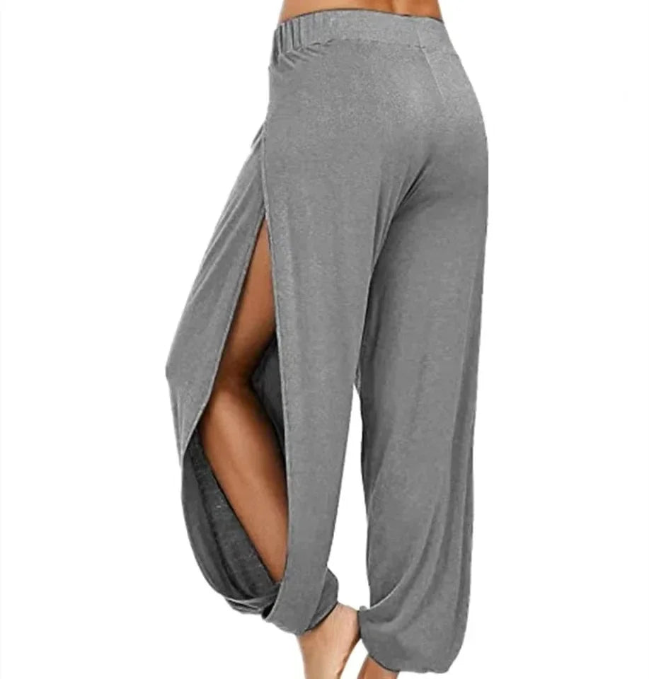 Model from the side-back wearing Echo & Air women's Ethereal Side-Slit Lounge Pants in gray showcasing the high leg slit and loose harem fit.