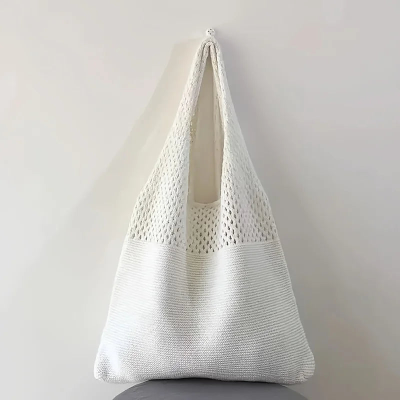 Echo & Air white crochet knit tote bag hanging from a wall hook against a minimalist background