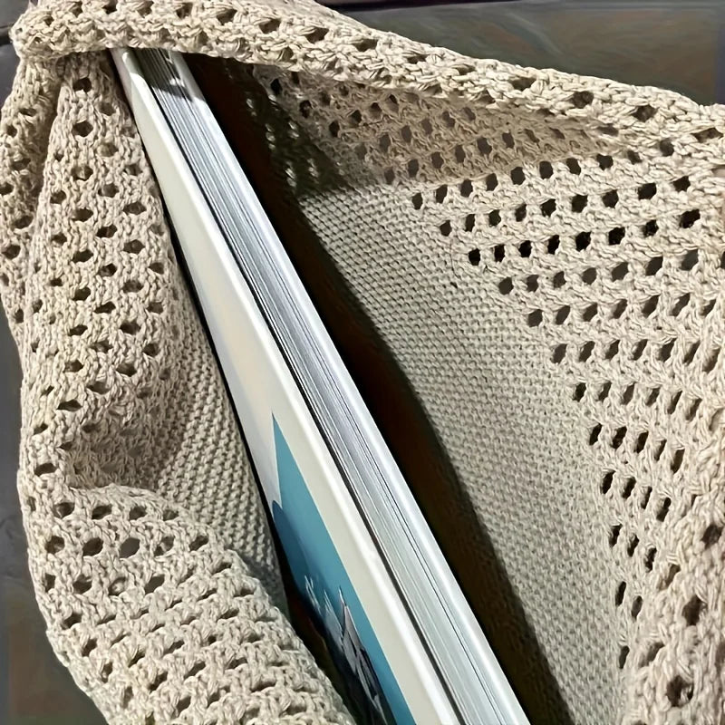 Close-up of the Echo & Air beige crochet knit tote bag showing the detailed cotton woven pattern and a book tucked inside.